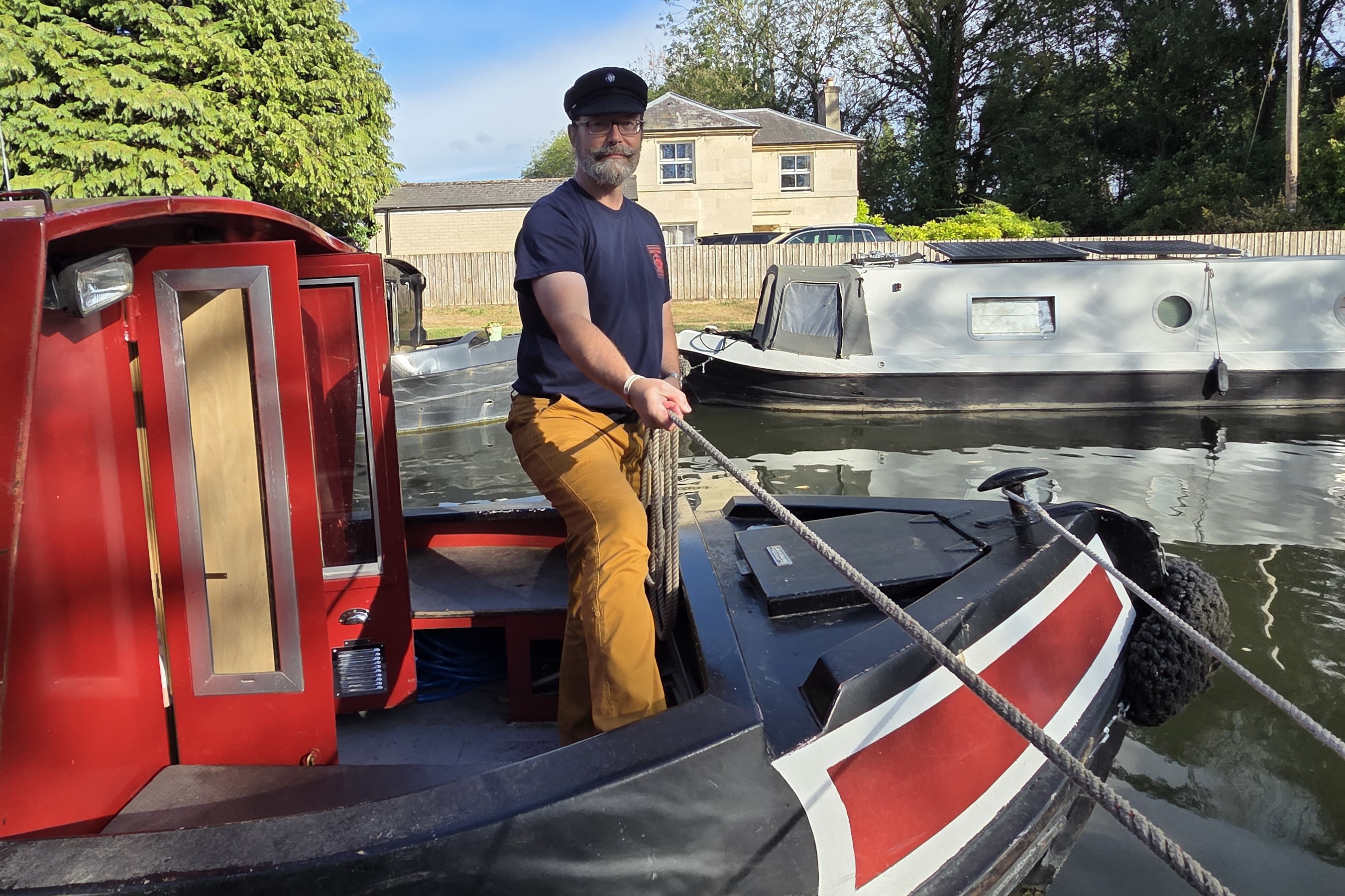 Jeffrey Fabiszewski wearing a navy Breton mariner's cap while handling a rope aboard a British narrowboat during a July 2025 American Sea Scout expedition in England.